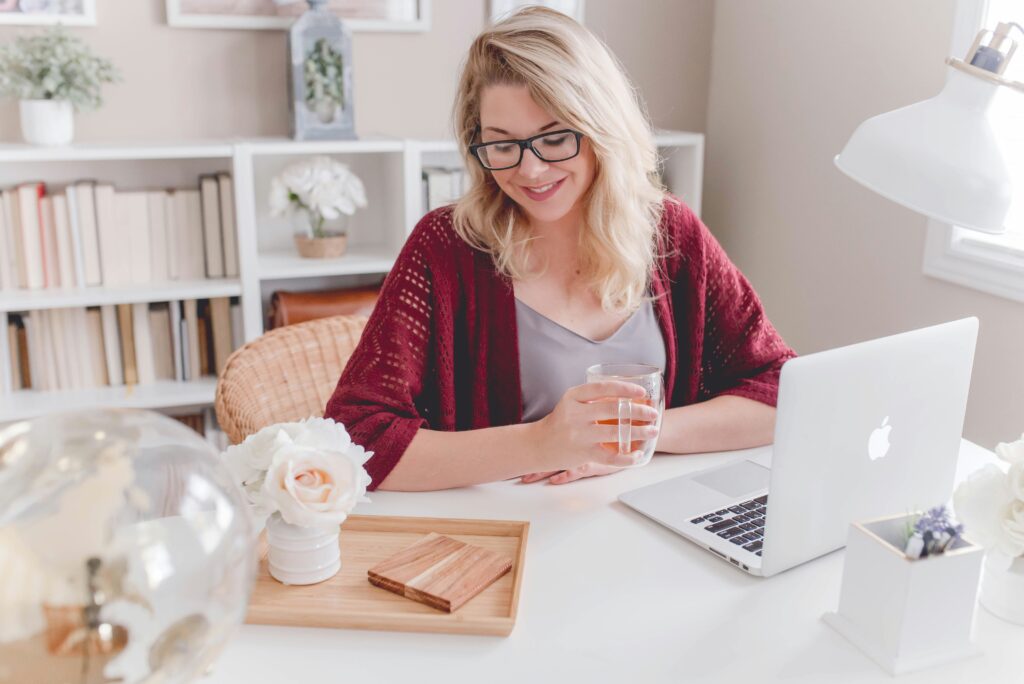 A blonde woman working at a desk in her home.